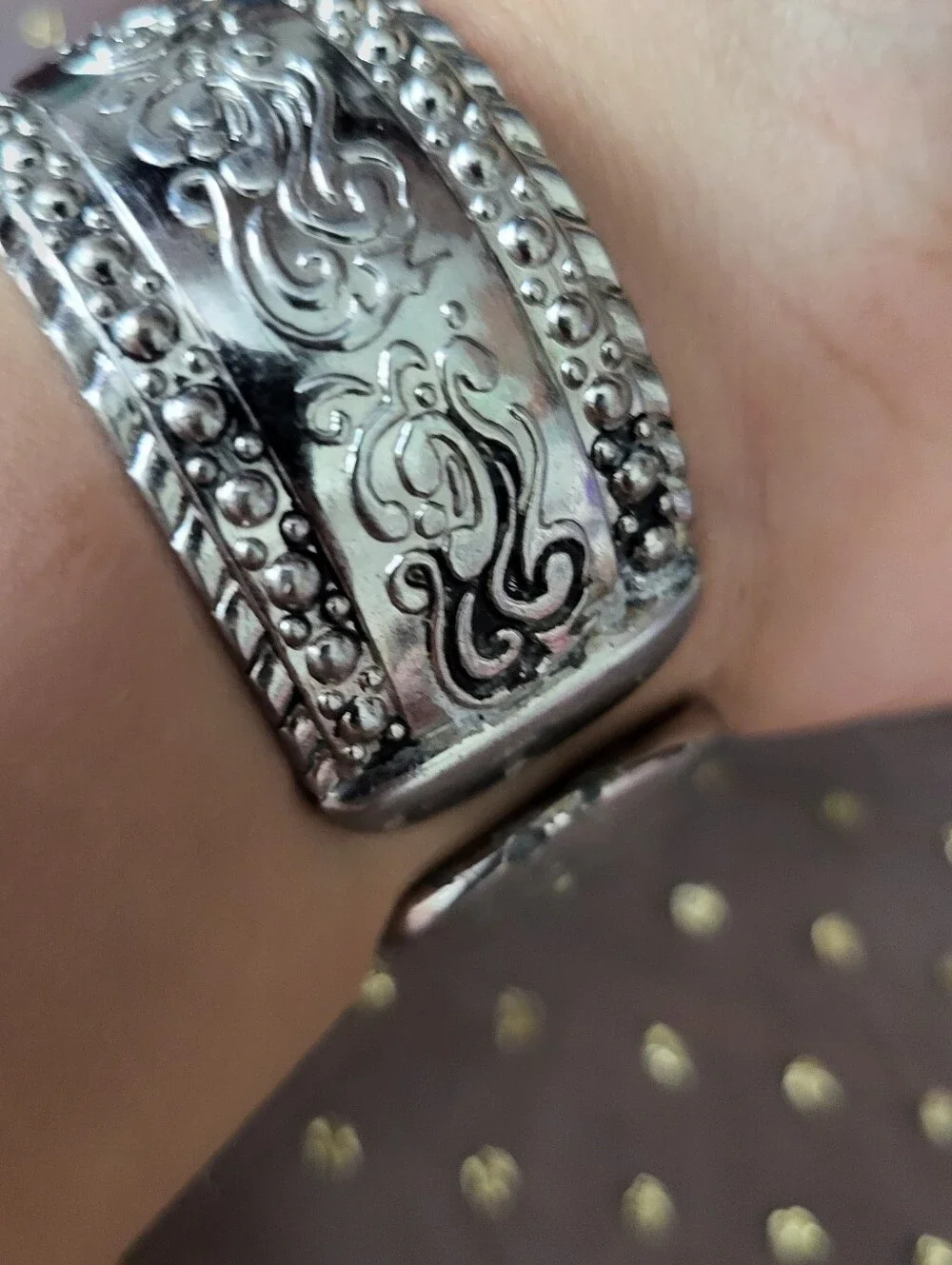 Silver bracelet watch with ornate scrollwork design has antique white face